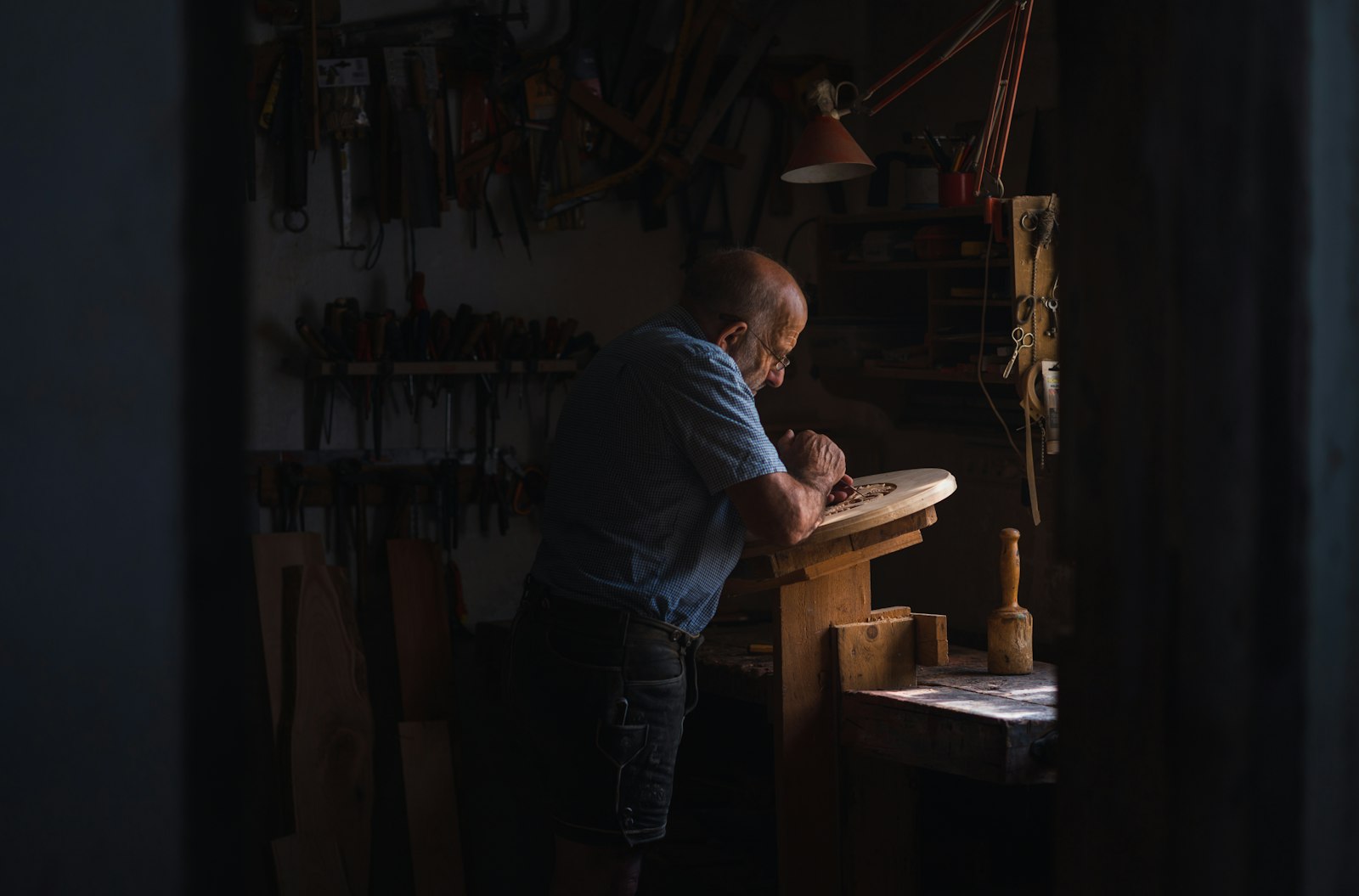 Artisan menuisier au travail dans son atelier, établi en bois et outils accrochés au mur