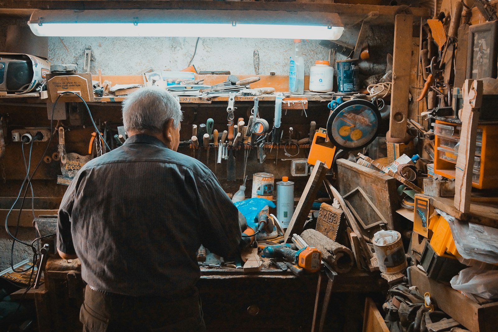 Artisan concentré à son établi d'atelier entouré d'outils, réparation sur mesure à L'Aiguillon-sur-Vie